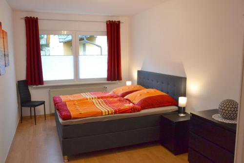 巴特Ferienhaus Leonie的一间卧室配有一张带红色窗帘的床和一扇窗户