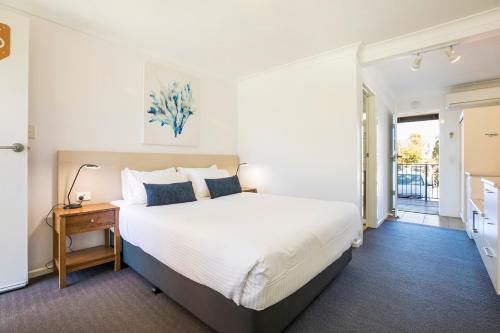 卡伦德拉金色海滩酒馆奈特卡普汽车旅馆的卧室配有一张白色的大床和一张桌子