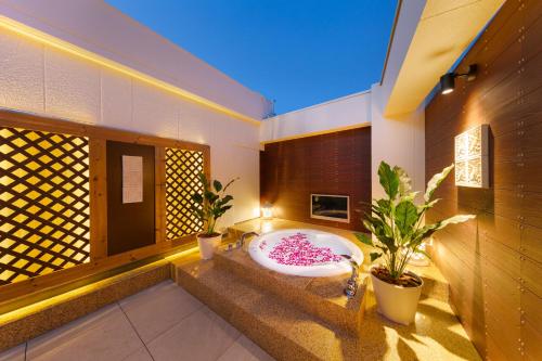 神户Hotel Eldia Modern Kobe(Adult Only)的带浴缸的浴室,种植了两株盆栽植物