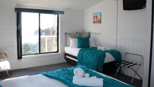 比那隆湾KINGFISHER COTTAGE Beachfront at the Binalong Bay的一间卧室设有两张床和窗户。