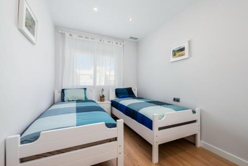 奥里韦拉斯科斯塔PENTHOUSE CABO ROIG - ALDEAS I的卧室设有两张床,拥有白色的墙壁和木地板