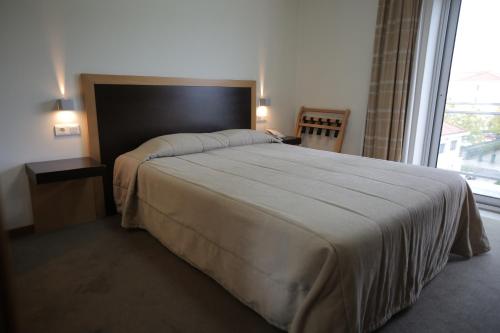 法蒂玛雷辛托酒店的一间卧室设有一张大床和大窗户