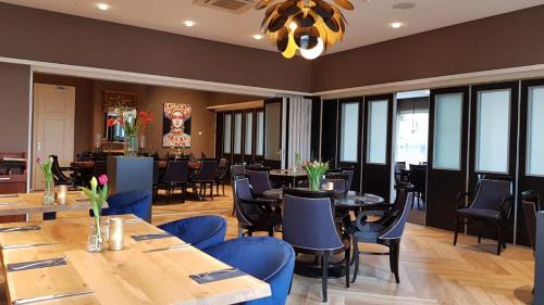 Hoogezand法贝尔酒店的餐厅设有木桌和蓝色椅子
