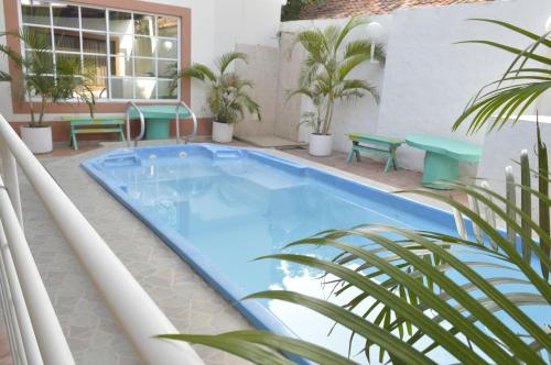 圣玛尔塔Hospedaje Villa Naloy的一个带植物和长椅的阳台的游泳池