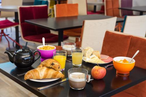 托尔西Brit Hotel Codalysa Marne la Vallée - Torcy的一张桌子,上面有早餐食品和饮料