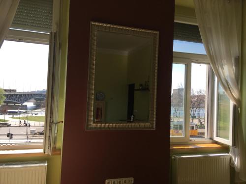 布达佩斯多瑙河pan工作室的一面镜子挂在两扇窗户旁的墙上