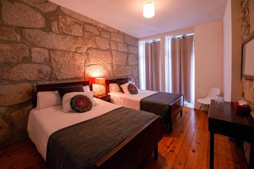 波尔图欧博托别墅的酒店客房设有两张床和石墙。