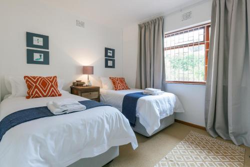 开普敦Seascape Cottage的一间卧室设有两张床和窗户。