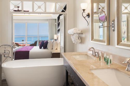 蒙特哥贝Jewel Grande Montego Bay Resort and Spa的带浴缸的浴室和1间带1张床的卧室