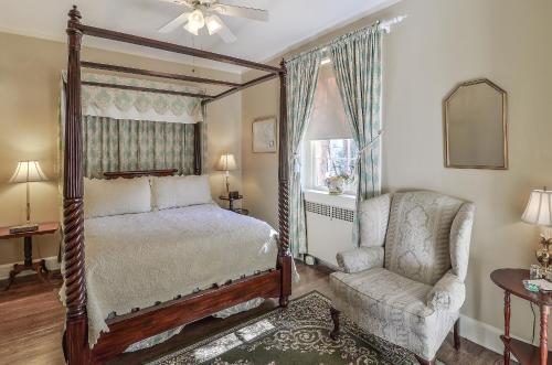 威廉斯堡威廉斯堡雪松住宿加早餐旅馆的一间卧室配有一张天蓬床和一把椅子