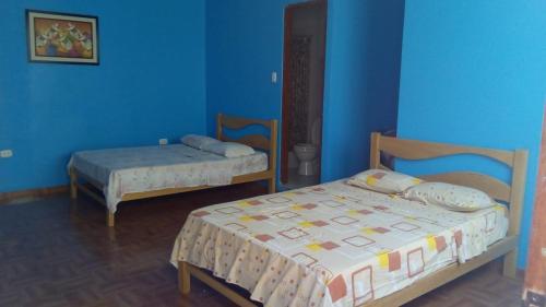 特鲁希略Hostal Virrey & Tours的一间卧室设有两张床和蓝色的墙壁
