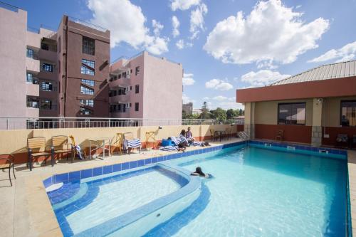 ThikaPaleo Hotel and Spa的在建筑物顶部的游泳池游泳的人