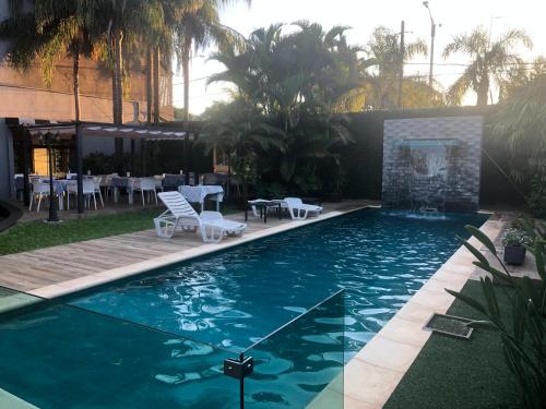 恩卡纳西翁Milord Hotel的庭院内一个带桌椅的游泳池