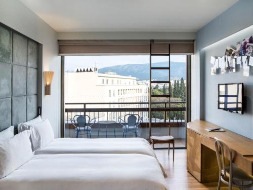 雅典尼欧酒店的一间卧室配有一张床、一张书桌和一个大窗户