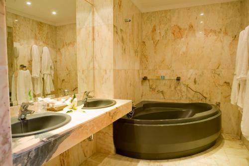 赫雷斯-德拉弗龙特拉拉库埃瓦公园酒店的一间带两个盥洗盆和大浴缸的浴室