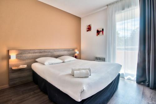 图卢兹图卢兹大都会泽尼图德公寓式酒店的一张大床,位于带大窗户的房间里