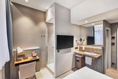不莱梅不来梅H5+酒店的一间带水槽的浴室和一张带电视的书桌
