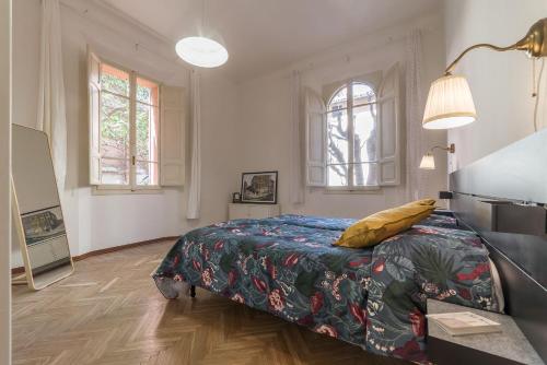 博洛尼亚Tilia的一间卧室配有一张床、一张桌子和两个窗户