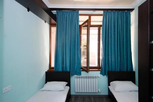 埃里温Hotel Victoria的客房设有两张床和一扇带蓝色窗帘的窗户。
