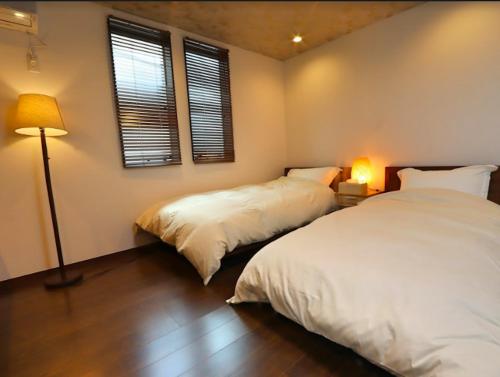 加贺BETTEI Yamashiro (別邸 山代)的配有两盏灯和窗户的客房内的两张床