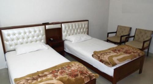 SargodhaSolo Hotel & Restaurant的配有2张椅子的客房内的2张床