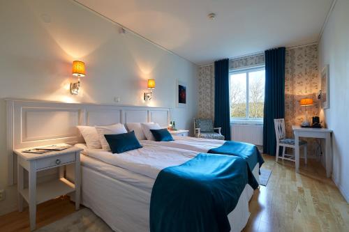 LyckeTofta Herrgård的一间卧室配有一张大床、一张桌子和一个窗户。