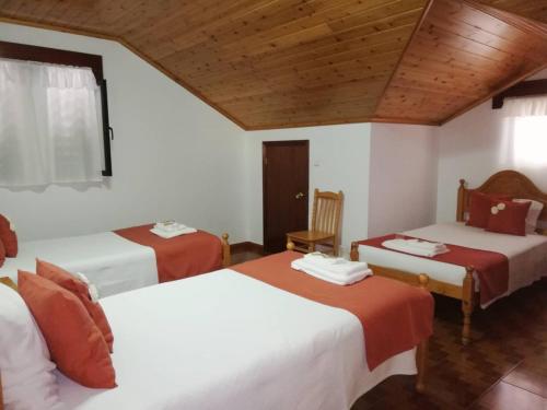 韦拉斯Residência Livramento的一间卧室设有两张床和木制天花板