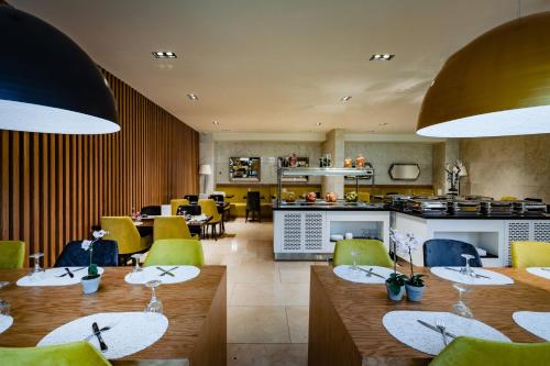 科纳克里里维埃拉皇家酒店的餐厅设有木桌和黄色椅子