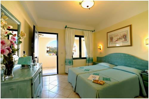 卡拉·利贝罗托Residence Cala Liberotto的一间卧室配有两张床和一张鲜花桌
