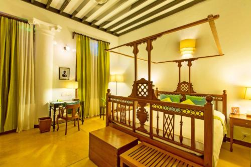 蓬蒂切里Maison Perumal Pondicherry - CGH Earth的一间卧室配有一张天蓬床、一张桌子和一张桌子。