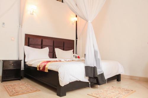 布琼布拉Hotel Kangaroo Bujumbura的一间卧室配有一张带白色床单的大床