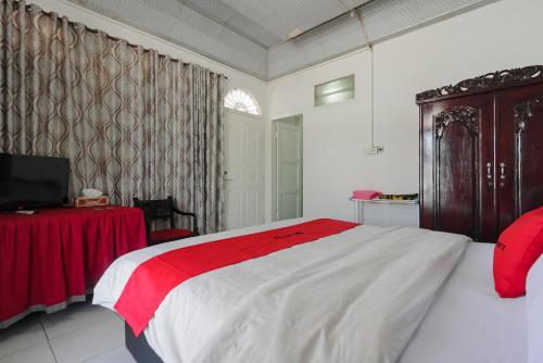 巴东RedDoorz Syariah near Universitas Negeri Padang的卧室配有红色和白色的床和桌子