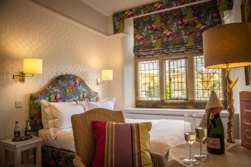 巴斯洛Fischers Baslow Hall - Chatsworth的一间卧室配有一张床和一张桌子及一杯葡萄酒