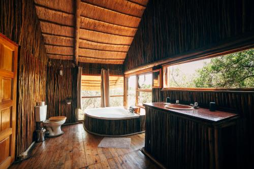 侯斯普瑞特Pezulu Tree House Lodge的带浴缸和卫生间的大型浴室
