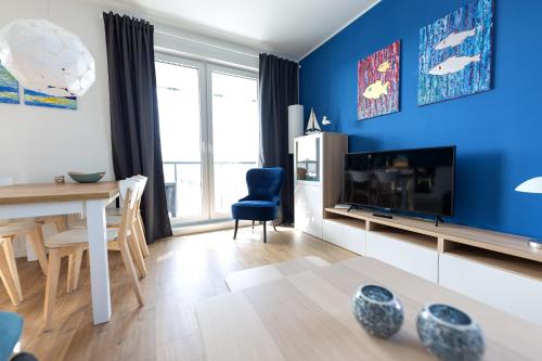 格但斯克波罗的海海滨塔公寓式酒店的客厅设有蓝色的墙壁、桌子和电视。