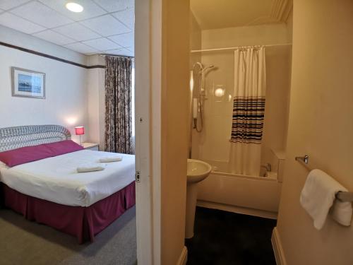 布莱克浦The Hopton Hotel的一间卧室配有一张床,浴室设有淋浴。