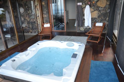 弗龙特拉Villa Tejeguate的一个带两把椅子的房间的按摩浴缸
