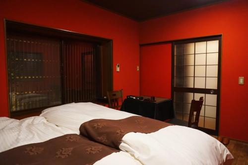 金泽金泽艾特苏士餐厅和旅馆的一间卧室设有红色的墙壁、两张床和窗户