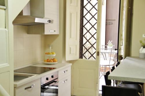 卡塔尼亚Dimora del sole的厨房配有白色橱柜和1张带1碗橙子的桌子