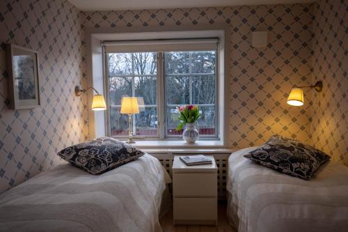 恩雪平Rekasta Bed & Breakfast的两张床位于带窗户和花瓶的房间