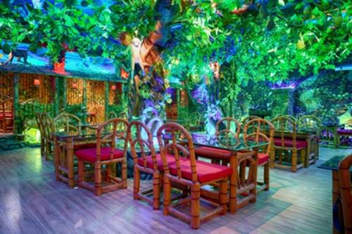 Alīpur DuārHotel Bangabhumi的一间设有桌椅和树木的餐厅