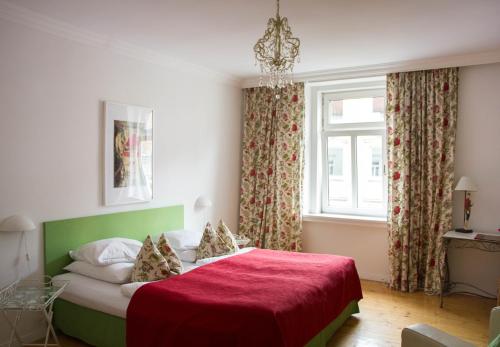 慕尼黑达斯慕尼黑酒店的一间卧室配有一张带红色毯子的床和窗户。
