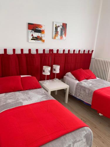 奥斯图尼Ostuni nuova casa vacanze的一间卧室配有两张带红色床单和桌子的床
