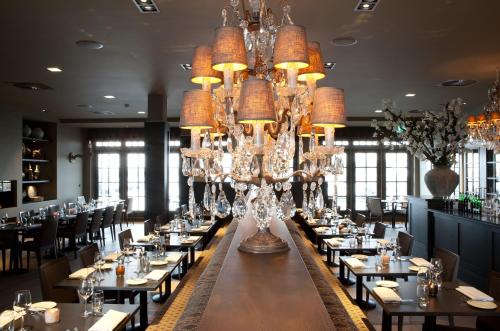 赫伊曾弗莱彻酒店 - 诺蒂什夸提尔餐厅的大型用餐室设有桌子和吊灯
