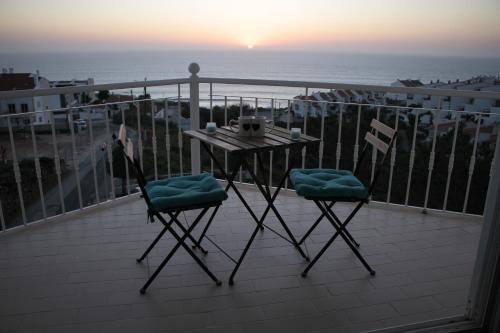 埃里塞拉Ericeira Sunset Apartment的阳台配有一张桌子和两把椅子,享有海景