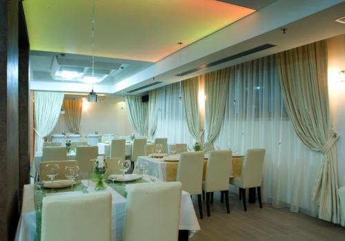 扎布利亚克索亚酒店的用餐室配有白色的桌子和白色的椅子