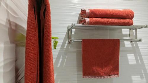 罗萨斯Apartamentos Ferrán Paqui的浴室毛巾架上的一组红色毛巾