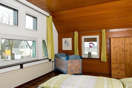 施莱登Ferienhaus im Grünen Eifel的一间卧室设有一张床和两个窗户。