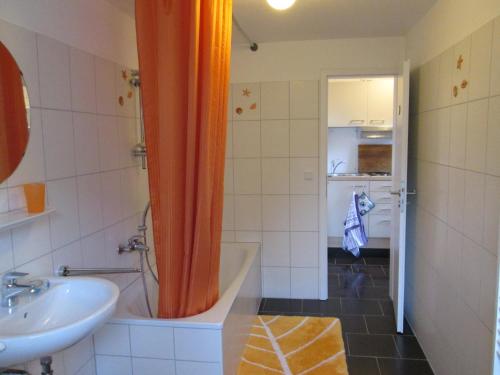诺登Haus Dreimaster Single-Wohnung ohne Wohnzimmer的浴室设有橙色淋浴帘和水槽