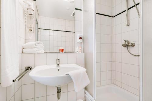 巴特哈尔茨堡Hotel Radau的白色的浴室设有水槽和淋浴。
